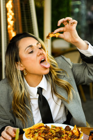 Young businesswoman eating nachos in a restaurant.の写真素材