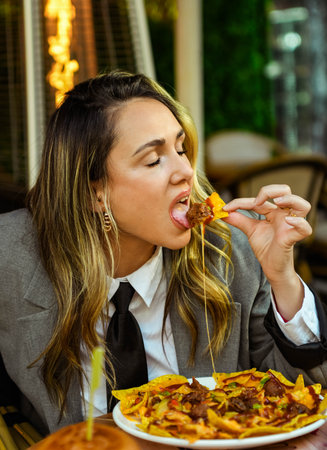 Young woman eating nachos with cheese in a restaurant. Fast food concept.の写真素材