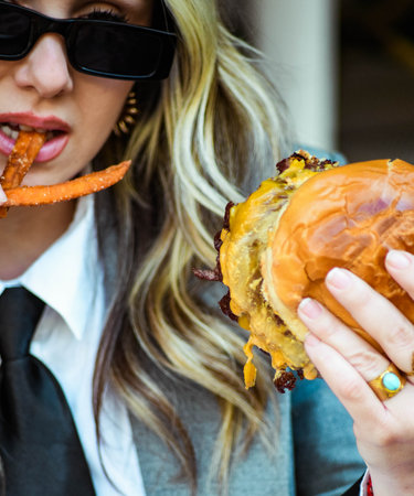 A young businesswoman eating a burger at an outdoor cafe