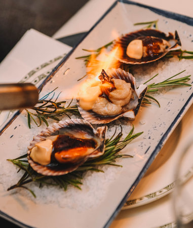 Grilled scallops with rosemary on a white plate.