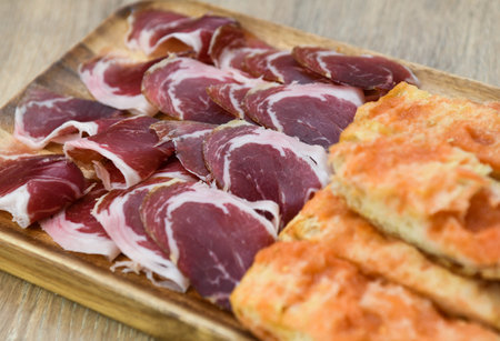 Slices of raw prosciutto on a wooden plate