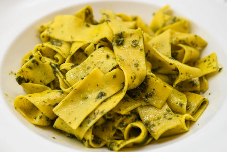 Pappardelle pasta with pesto sauce on a white plateの写真素材
