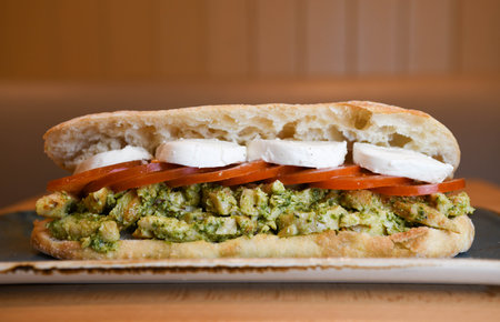 Pesto sandwich with tomatoes and mozzarella cheese.