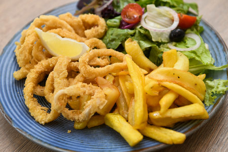 Fried squid rings with french fries and saladの写真素材