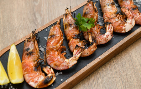 Grilled tiger prawns with lemon and parsley on wooden tableの写真素材
