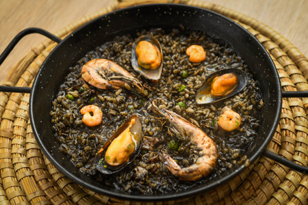 Paella with mussels in a wok on a wooden tableの写真素材