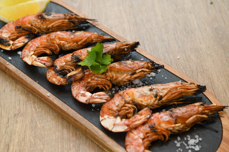 Grilled tiger prawns with lemon and parsley on wooden tableの写真素材