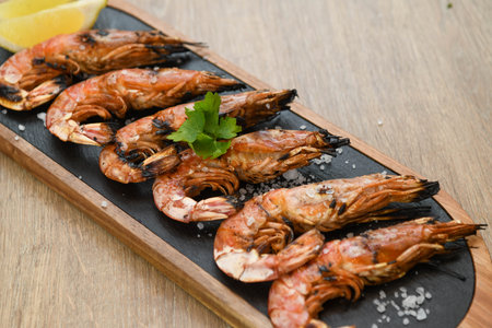 Grilled tiger prawns with lemon and parsley on wooden tableの写真素材