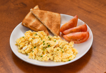 Scrambled Eggs with Toast and Tomato on a Plateの写真素材