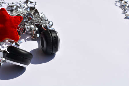 Headphones and silver Christmas decoration on white background. Top view, copy space.