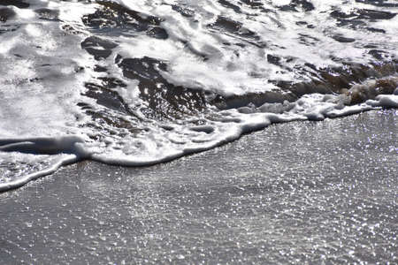Frothy wave reaching the beach sand