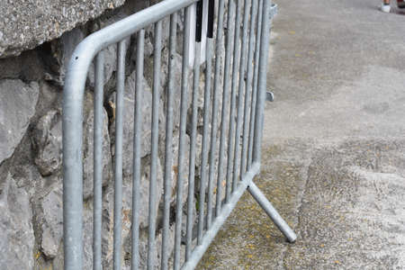 Metal barrier on the street next to a stone wallの写真素材