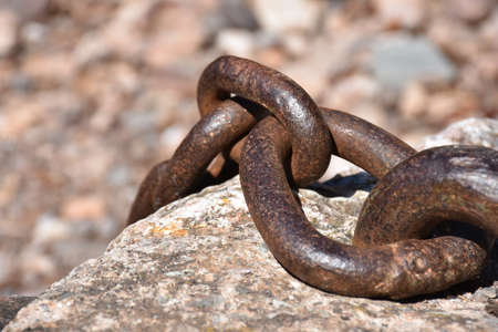 Thick metallic chain nailed to a rockの写真素材