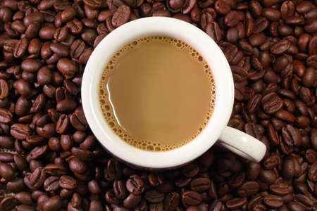 A cup of coffee milk with coffee bean as backgroundの写真素材
