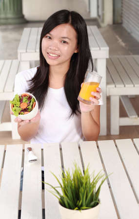 young lady eating vegetable salad at a restaurantの写真素材