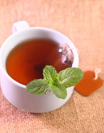 A cup of tea with mint leaves on a sack simple backgroundの写真素材