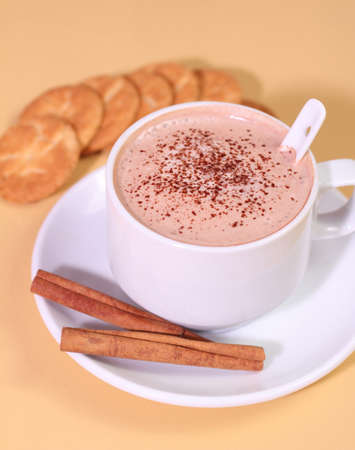 Hot chocolate milk drink, cinnamon and biscuit on a yellow backgroundの写真素材