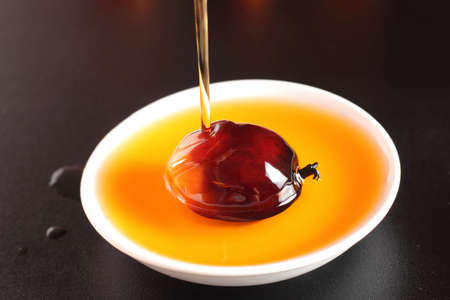 Pouring cooking oil into white plate with oil palm fruitの写真素材