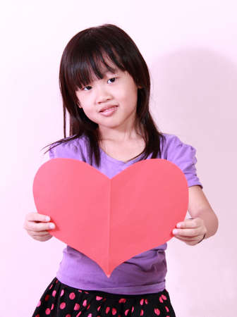 A cute little girl holding a heart shape paperの写真素材