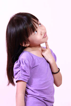cute little girl looking up and thinkingの写真素材