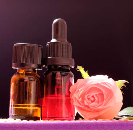 Two bottles essential oil and rose flower on bamboo mat, come on, let's go spa.の写真素材