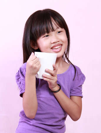 A cute little girl holding a cup of drinkの写真素材