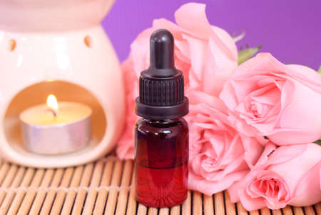 One bottle of essential oil and rose flowers on bamboo matの写真素材