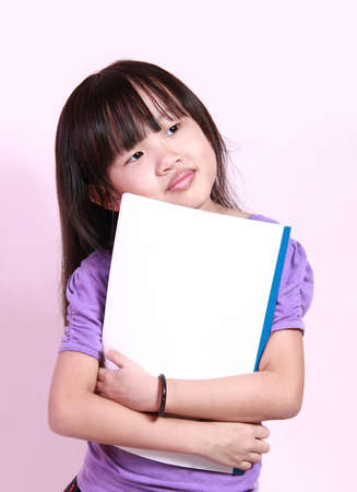 A cute little girl holding a bookの写真素材