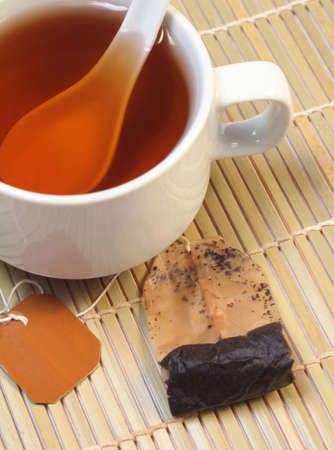 A cup of tea with tea bag on a bamboo matの写真素材
