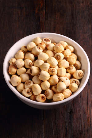 A group of dried lotus seeds in bowl on wooden tableの写真素材