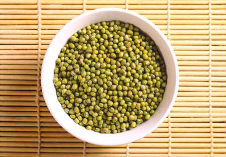 Bowl of dried green beans on yellow bamboo mat backgroundの写真素材
