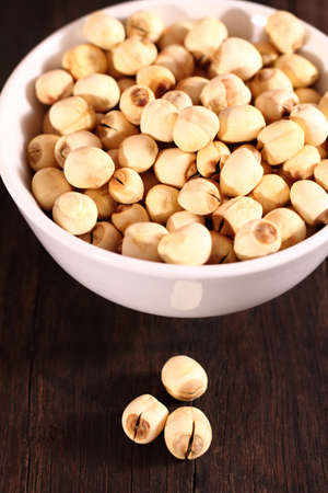 A group of dried lotus seeds in bowl on wooden tableの写真素材