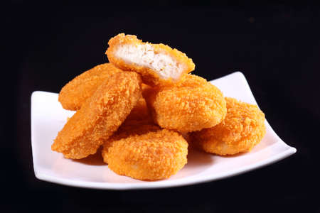 A pile of chicken nuggets on white plate with black color backgroundの写真素材