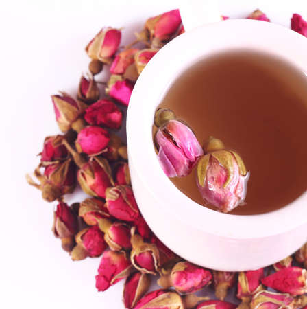 A glass of rose tea and dried roses on a white backgroundの写真素材