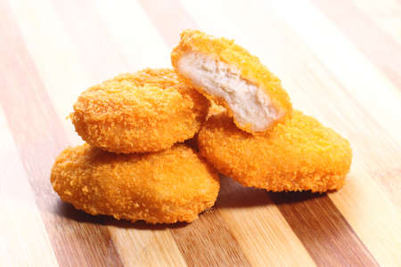 A pile of chicken nuggets on a wooden cutting boardの写真素材
