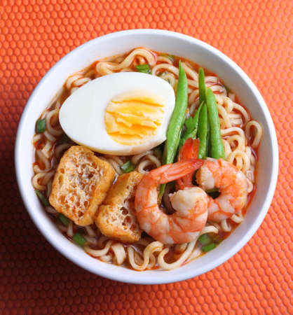 Hot and spicy instant noodle isolated on the orange color backgroundの写真素材