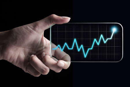 Hand showing a rising graph on tablet, representing business growth. The background is black, chart colors are white and blue.の写真素材