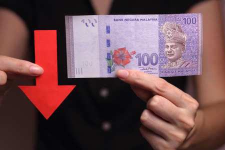 Malaysian Ringgit with a red arrow to imply the fall or devaluation of Malaysian ringgit currencies.の写真素材