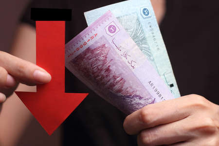Malaysian Ringgit with a red arrow to imply the fall or devaluation of Malaysian ringgit currencies.の写真素材