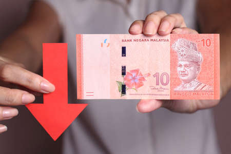 Malaysian Ringgit with a red arrow to imply the fall or devaluation of Malaysian ringgit currencies.の写真素材