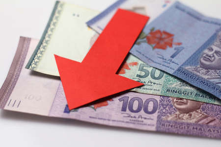 Malaysian Ringgit with a red arrow to imply the fall or devaluation of Malaysian ringgit currencies.の写真素材