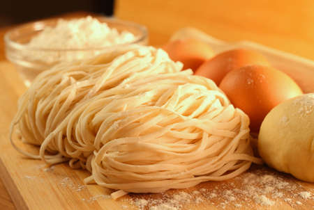 Handmade noodles and ingredients on chopping block. Noodles are an essential ingredient and staple in Chinese cuisine.の写真素材