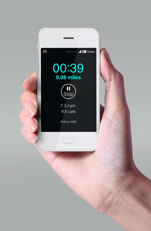 Smartphone, jogging application with hand on grey background.の写真素材