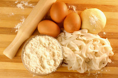 Handmade noodles and ingredients on chopping block. Noodles are an essential ingredient and staple in Chinese cuisine.の写真素材