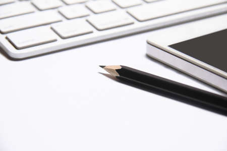 Tablet, pencil and keyboard on white office table.
