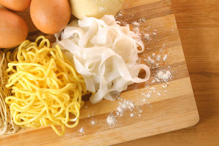Handmade noodles and ingredients on chopping block. Noodles are an essential ingredient and staple in Chinese cuisine. の写真素材