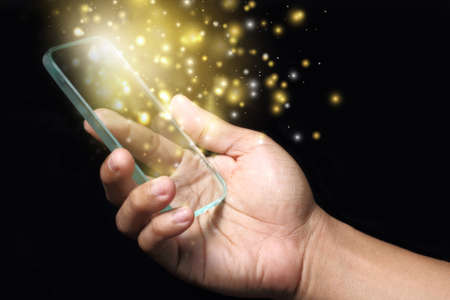 Hand showing gold color magic stars light on smartphone