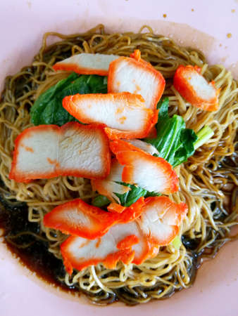 Wonton noodles is a Cantonese noodle dish which is popular in asia. The dish is usually served in a hot broth, garnished with leafy vegetables, and wonton dumplings.の写真素材