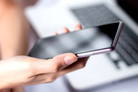 Hand holding mobile smartphone with blank screen. A smartphone is a mobile or cellular phone that...