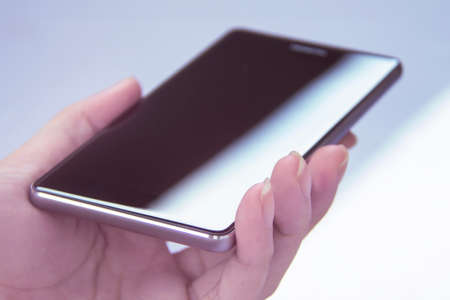 Hand holding mobile smartphone with blank screen. A smartphone is a mobile or cellular phone that runs off a mobile operating system and functions like a mini computer .の写真素材